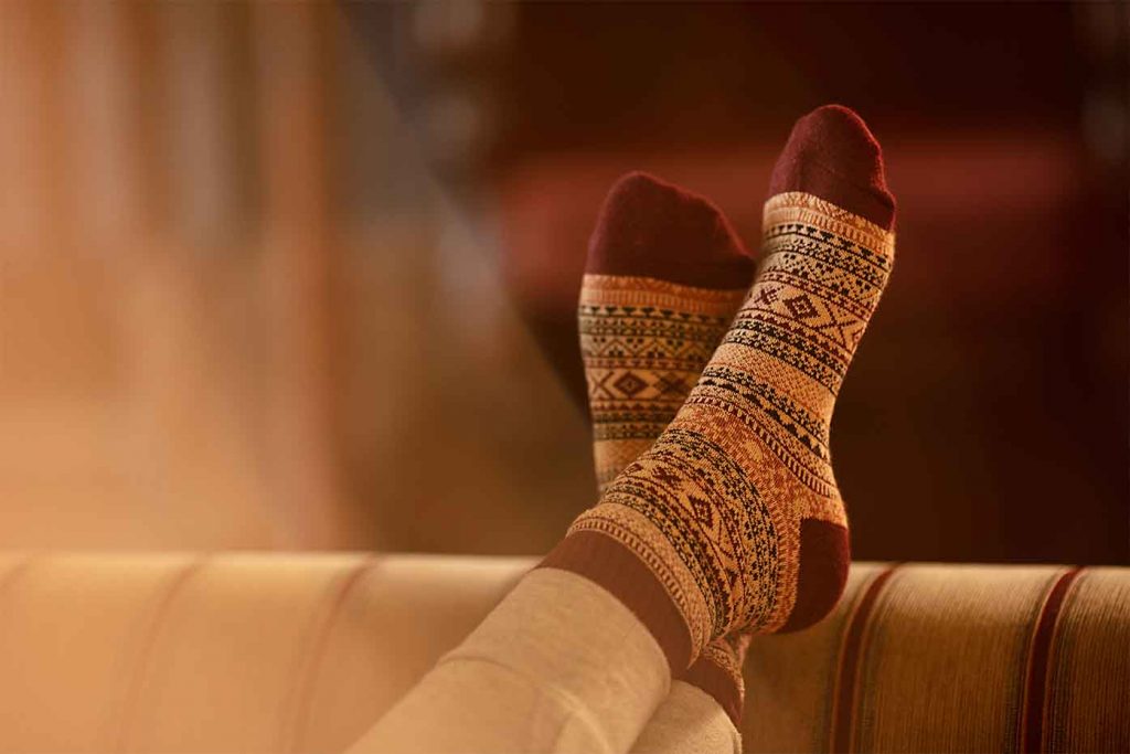 Feet in comfy socks resting on arm of sofa