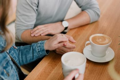 two people holding hands drinking coffee